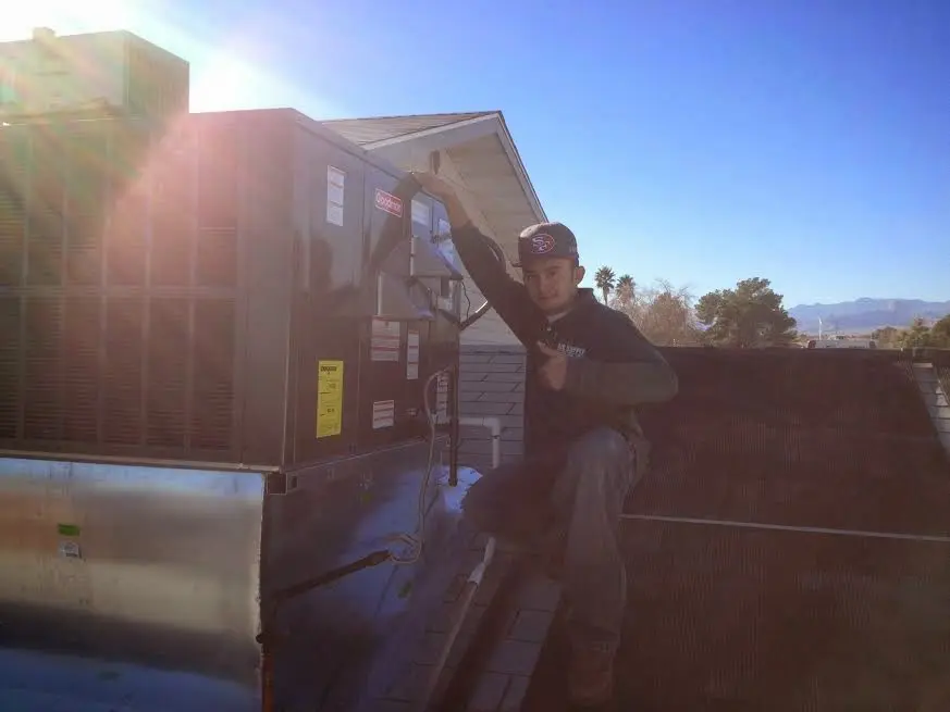 HVAC technician performing Air Duct Repair on a rooftop unit in Arkansas City